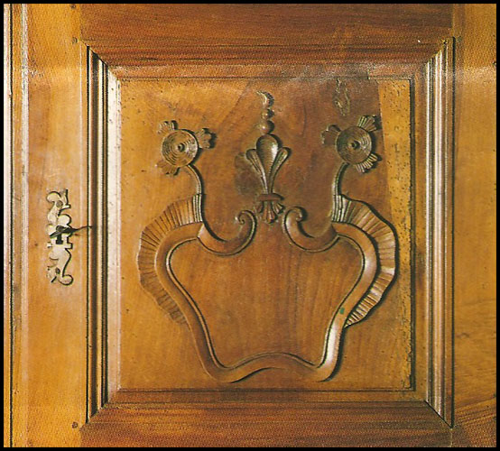 Détail d'un quatre-portes en noyer avec motif Régence ourlé de rubans plissés, fleurs de lis entre marguerites, en l'honneur de la Marguerite des Marguerites, grand-mère de Henri IV